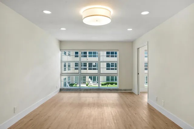 an empty room with wooden floor and window