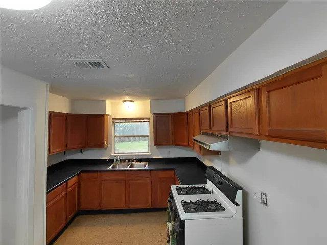 a kitchen with granite countertop a sink a stove and cabinets