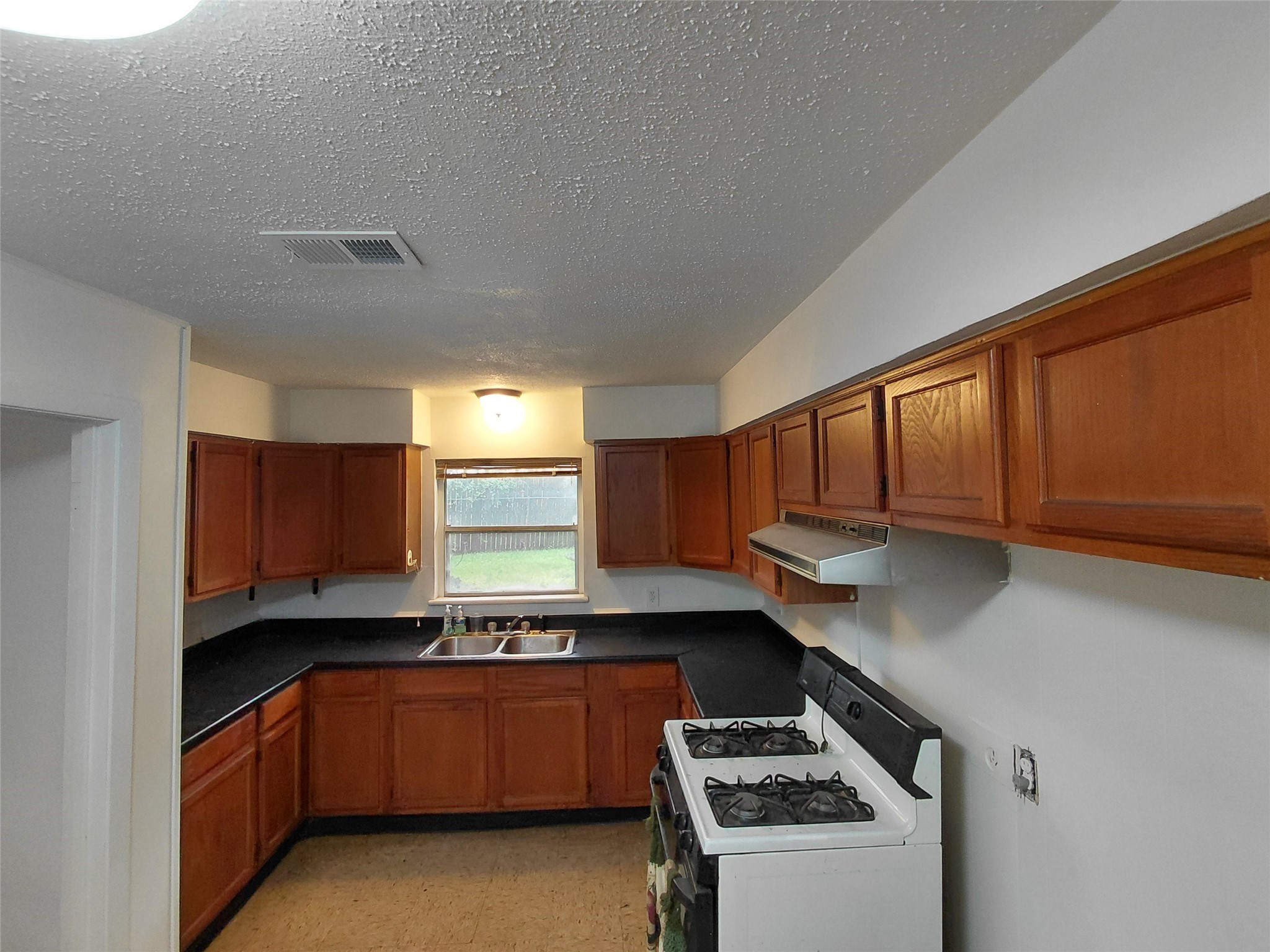 201 Delta Street Pasadena, TX 77506 - Photo 16 of 19 a kitchen with granite countertop a sink a stove and cabinets