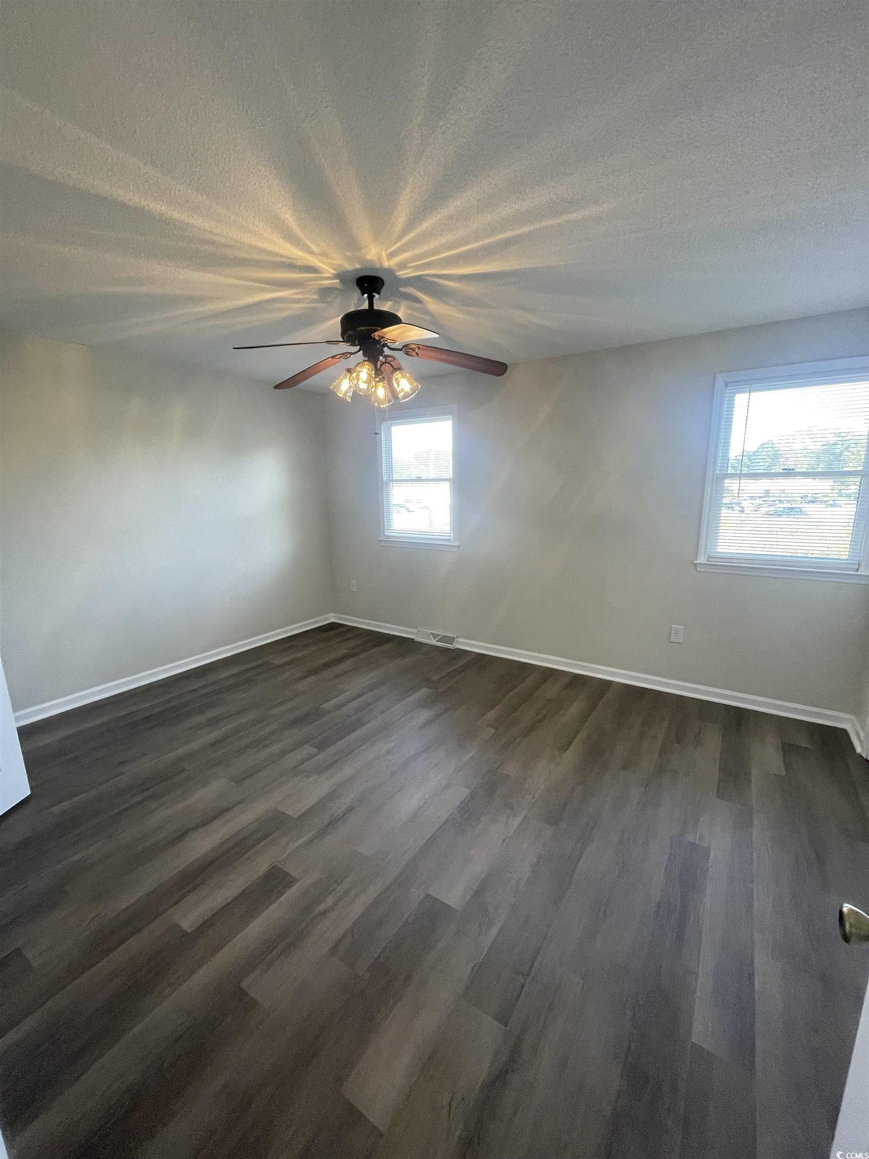 4641 Socastee Boulevard, Unit E1 Myrtle Beach, SC 29588 - Photo 11 of 20 Spare room featuring dark wood-style flooring, a ceiling fan, and a textured ceiling
