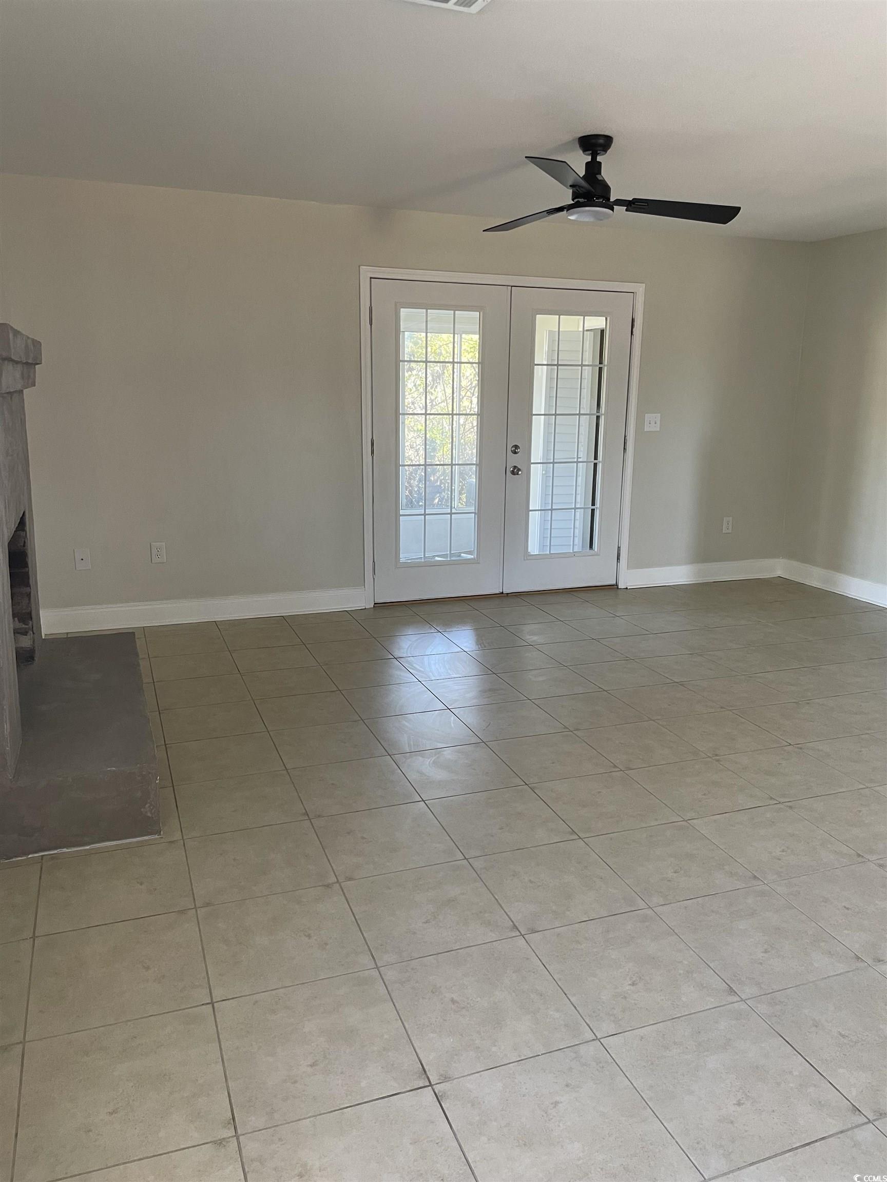 4641 Socastee Boulevard, Unit E1 Myrtle Beach, SC 29588 - Photo 17 of 20 Unfurnished living room featuring french doors, light tile patterned floors, a ceiling fan, and a glass covered fireplace