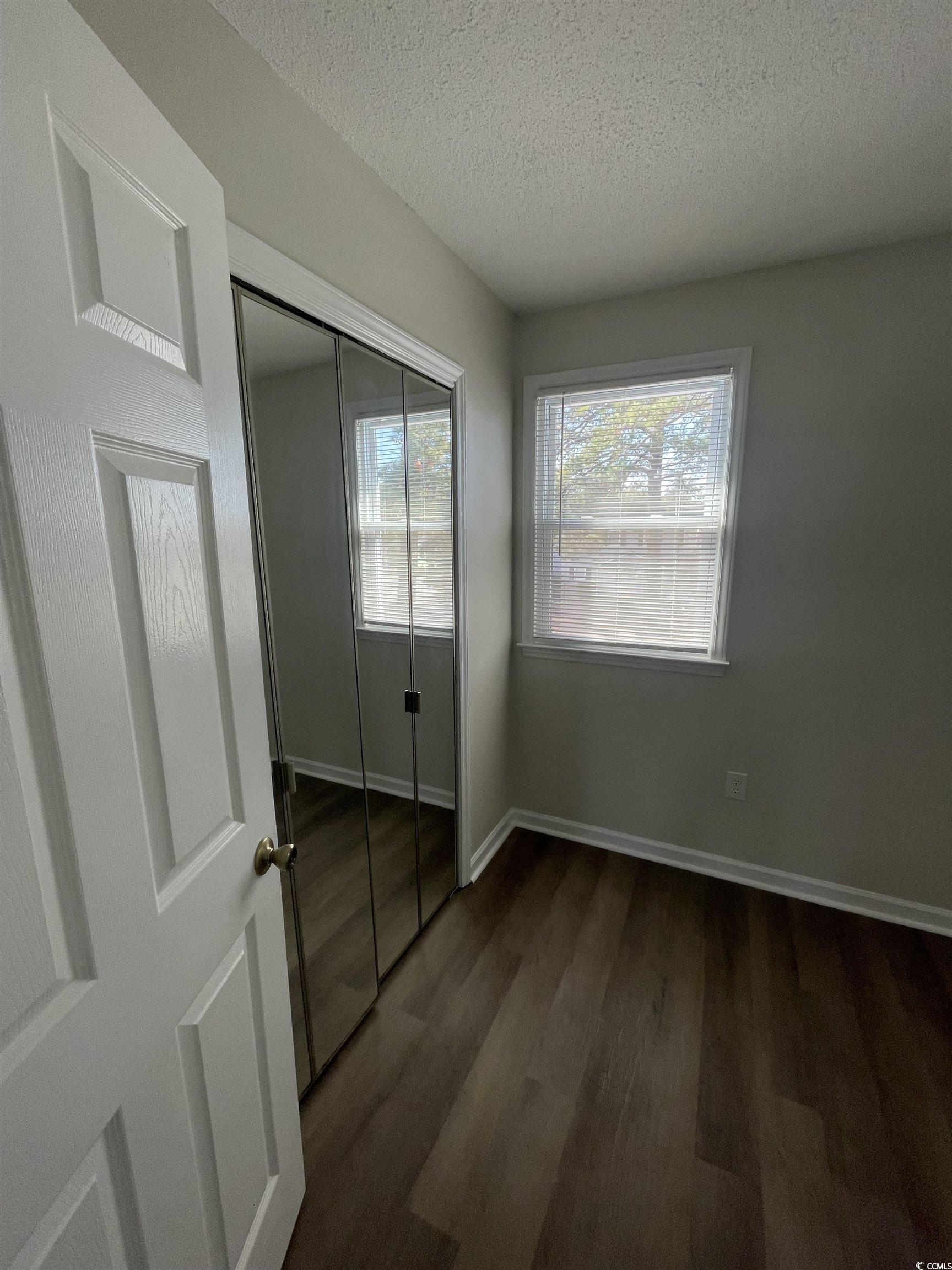 4641 Socastee Boulevard, Unit E1 Myrtle Beach, SC 29588 - Photo 5 of 20 Unfurnished bedroom featuring a textured ceiling, dark wood-type flooring, and a closet