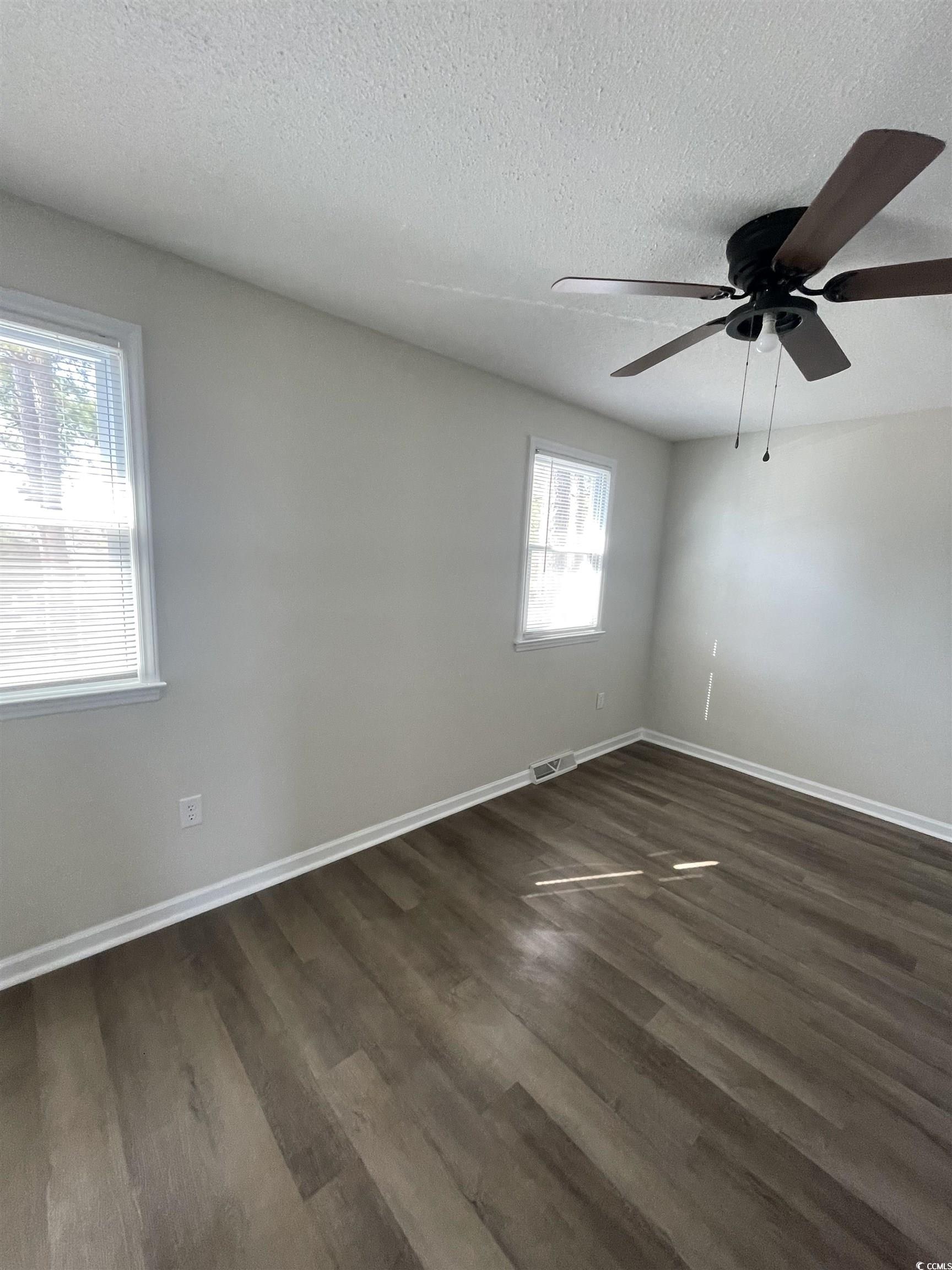 4641 Socastee Boulevard, Unit E1 Myrtle Beach, SC 29588 - Photo 8 of 20 Unfurnished room with a textured ceiling, dark wood-type flooring, and a ceiling fan