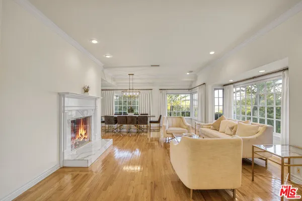a living room with fireplace furniture wooden floor and a large window