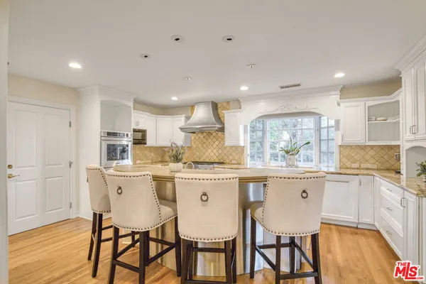 a kitchen with a dining table chairs wooden floor cabinets and stainless steel appliances