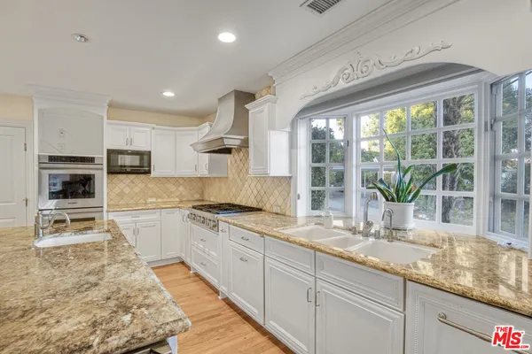 a kitchen with stainless steel appliances granite countertop a sink a stove and a wooden floors