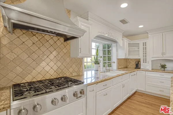 a kitchen with granite countertop a stove and white cabinets