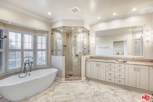 a spacious bathroom with a granite countertop double vanity sink a mirror a bathtub and window