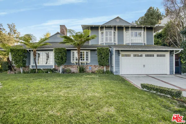 a front view of a house with a garden and plants