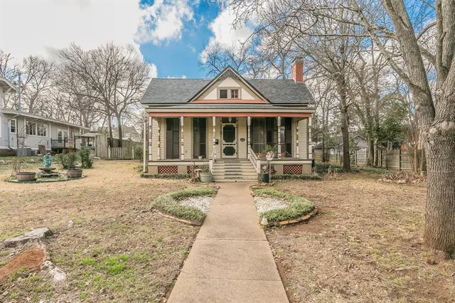 a view of a white house with large windows next to a yard with palm trees