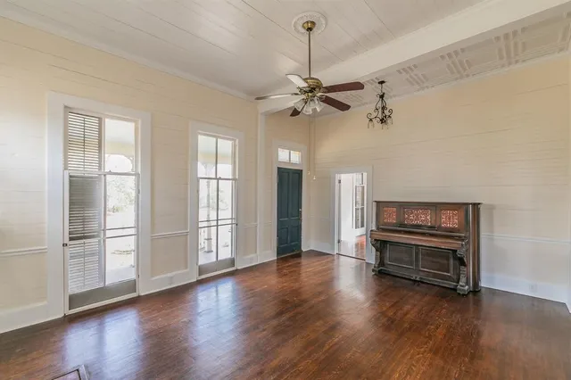 an empty room with wooden floor fireplace and windows