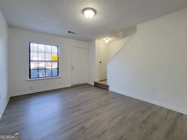 an empty room with wooden floor and windows