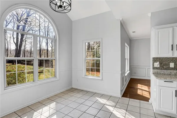 a view of a livingroom with wooden floor a ceiling fan and windows