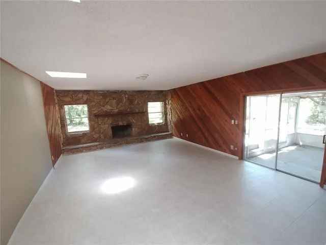 an empty room with windows and fireplace