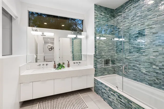 a bathroom with a double vanity sink a mirror and bathtub