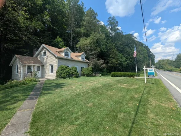 a view of house with a big yard and large trees