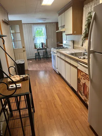 a kitchen with stainless steel appliances granite countertop a refrigerator a stove a sink dishwasher and white cabinets with wooden floor