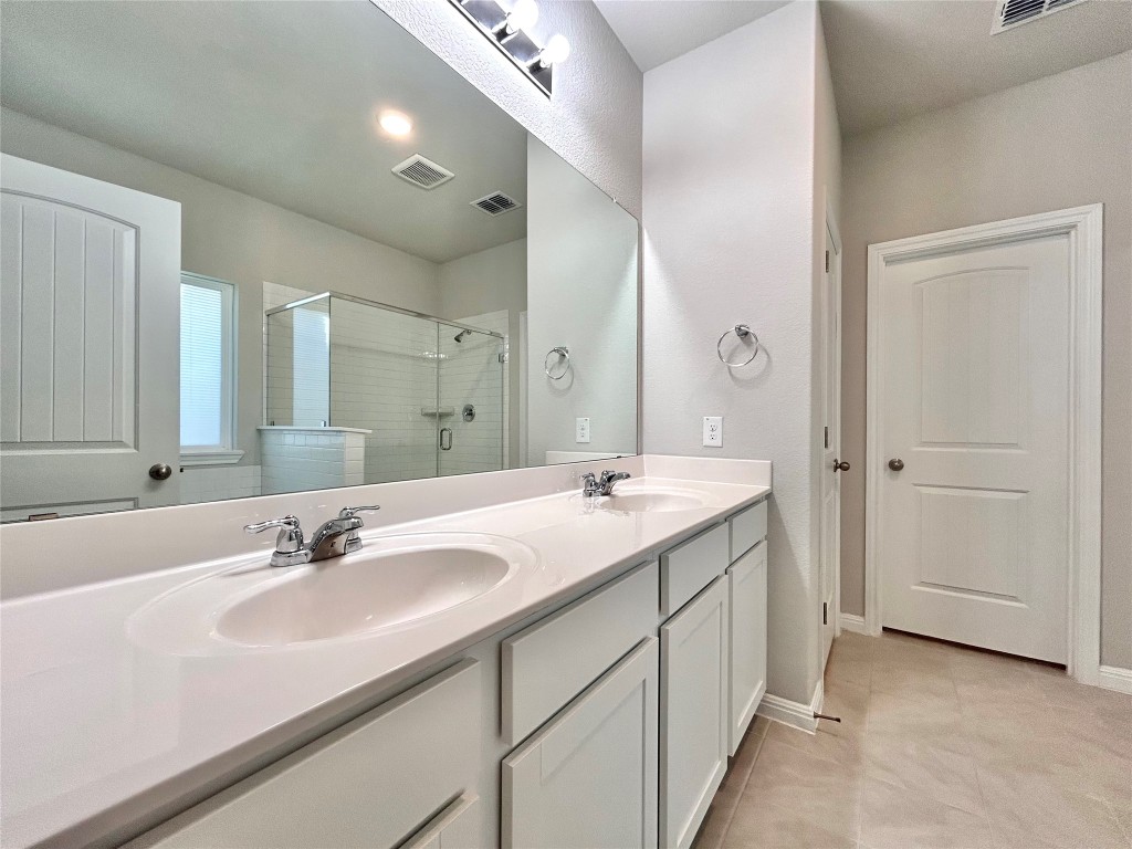 13104 Zumpango Trace Manor, TX 78653 - Photo 16 of 37 Full bathroom with double vanity, a stall shower, and light tile patterned floors