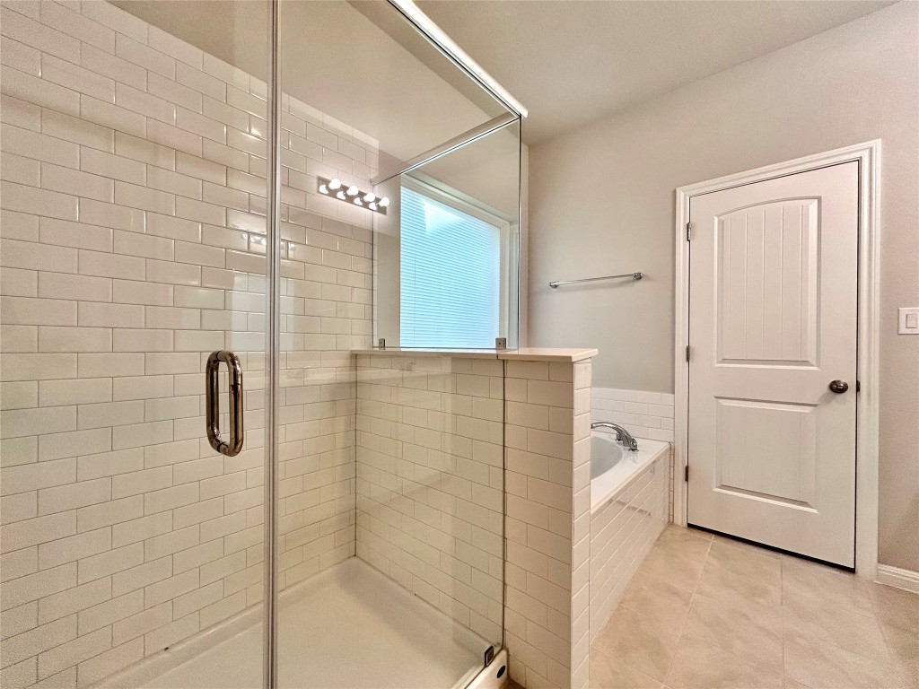13104 Zumpango Trace Manor, TX 78653 - Photo 18 of 37 Full bathroom featuring a bath, a stall shower, and light tile patterned floors