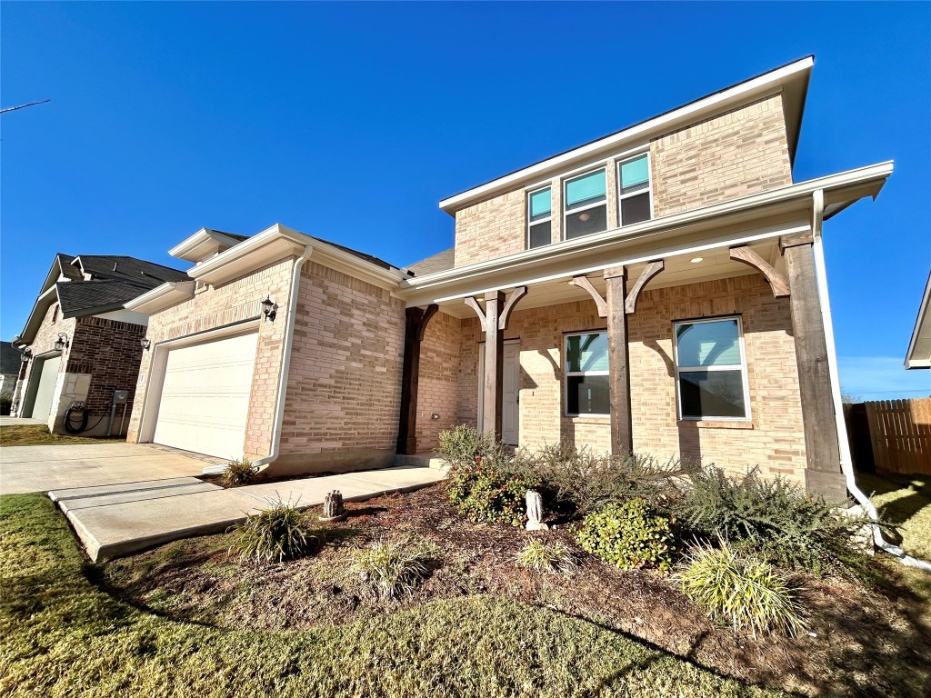 13104 Zumpango Trace Manor, TX 78653 - Photo 2 of 37 View of front of home with brick siding, an attached garage, covered porch, and driveway