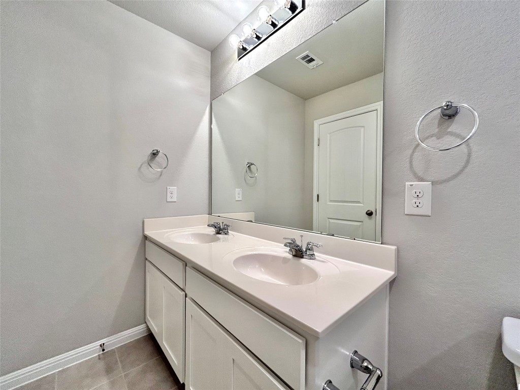 13104 Zumpango Trace Manor, TX 78653 - Photo 29 of 37 Full bathroom featuring double vanity, a textured wall, and light tile patterned floors
