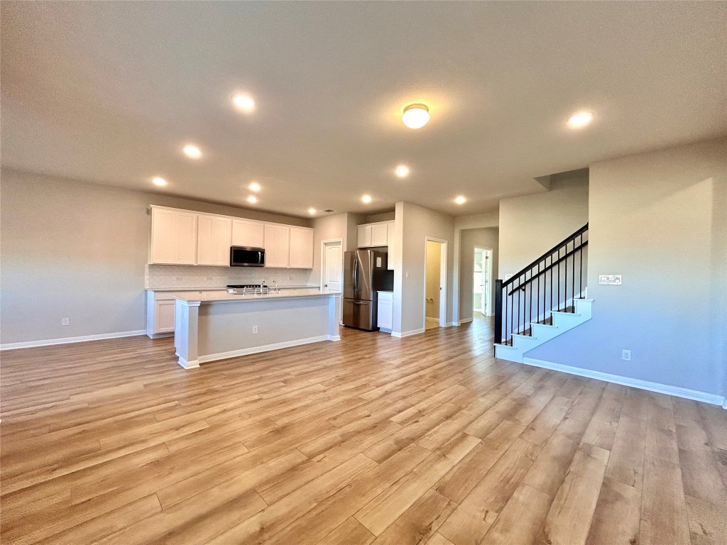 13104 Zumpango Trace Manor, TX 78653 - Photo 36 of 37 Kitchen with open floor plan, light countertops, white cabinetry, a center island with sink, and appliances with stainless steel finishes