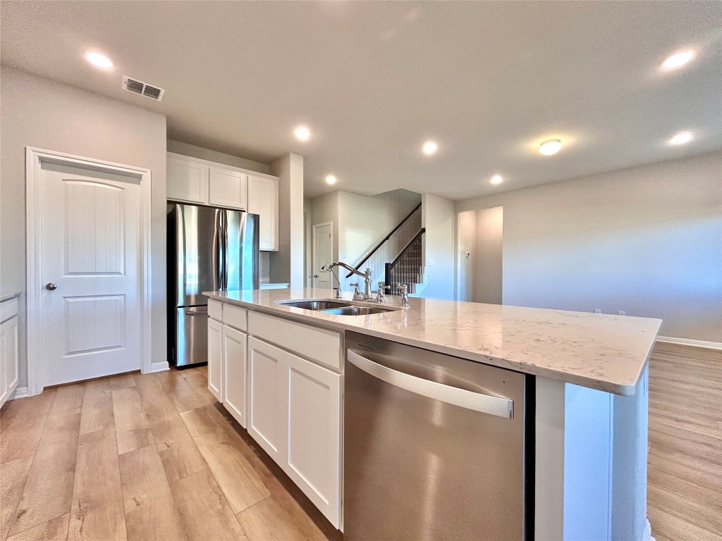 13104 Zumpango Trace Manor, TX 78653 - Photo 6 of 37 Kitchen with appliances with stainless steel finishes, white cabinets, light wood-style flooring, a center island with sink, and recessed lighting