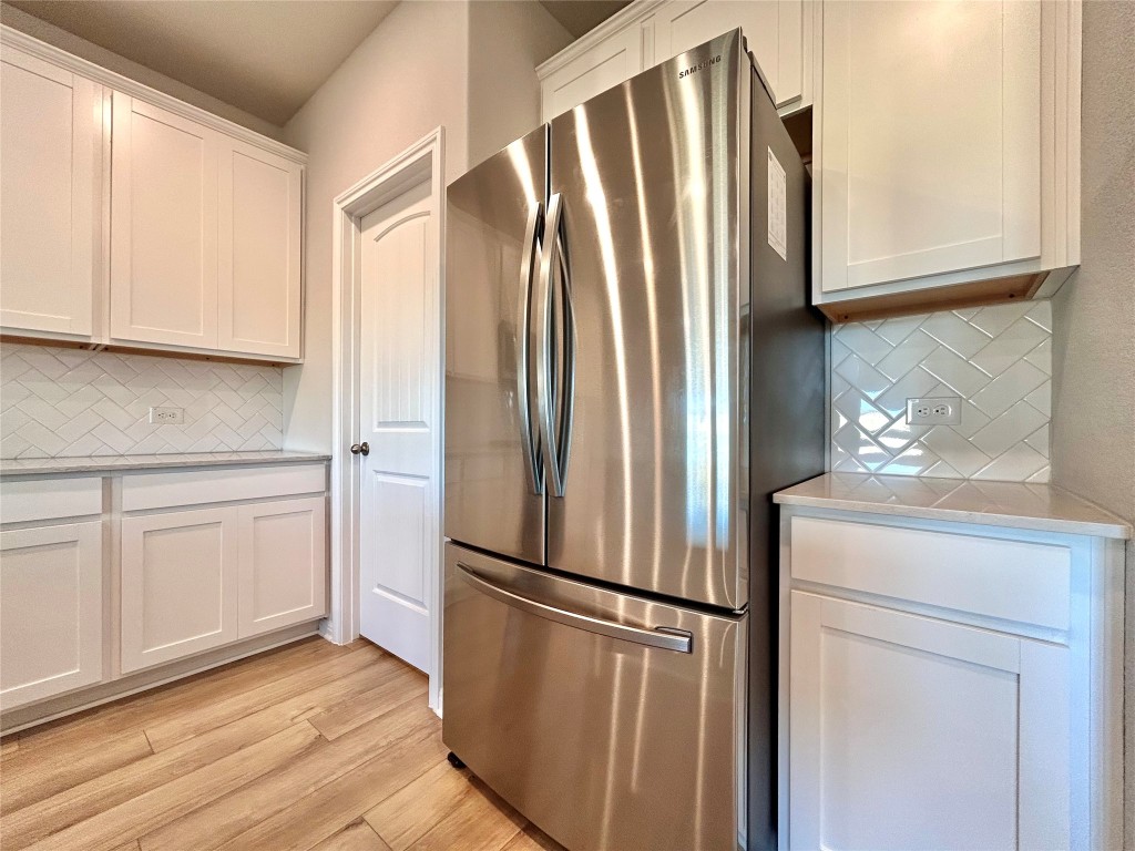 13104 Zumpango Trace Manor, TX 78653 - Photo 9 of 37 Kitchen featuring backsplash, freestanding refrigerator, and white cabinets