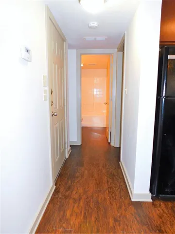 a view of a hallway with wooden floor and a bathroom