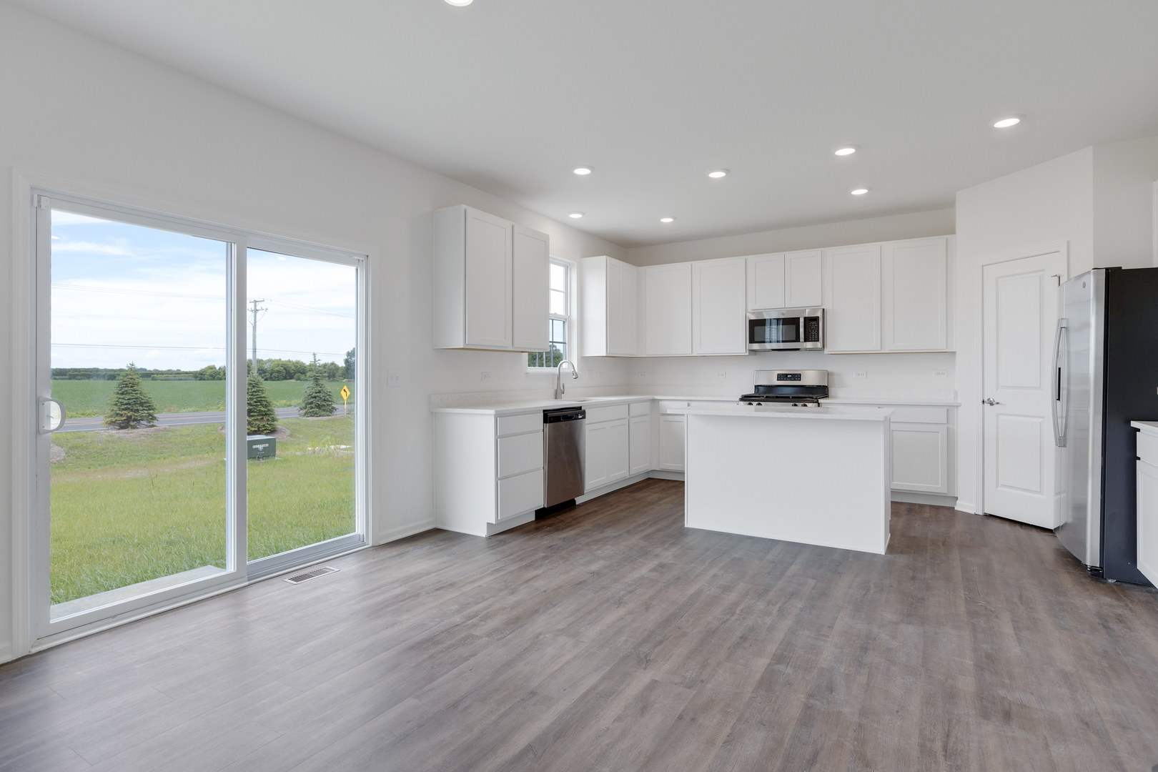 1464 Collins Street Elburn, IL 60119 - Photo 3 of 15 a kitchen with white cabinets and white appliances with wooden floor