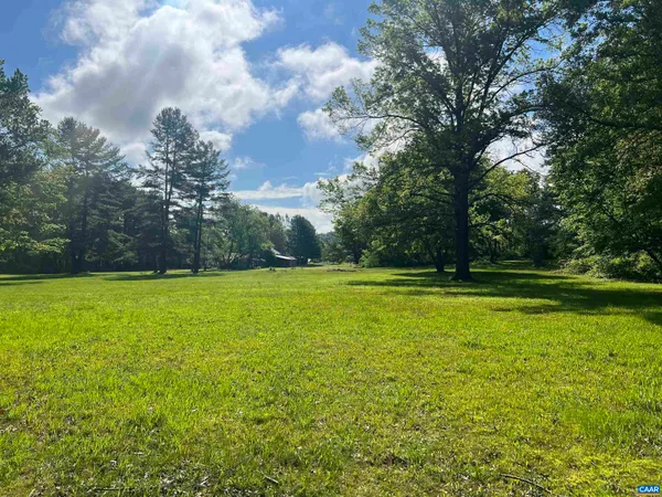 a view of a big yard with a trees in the background