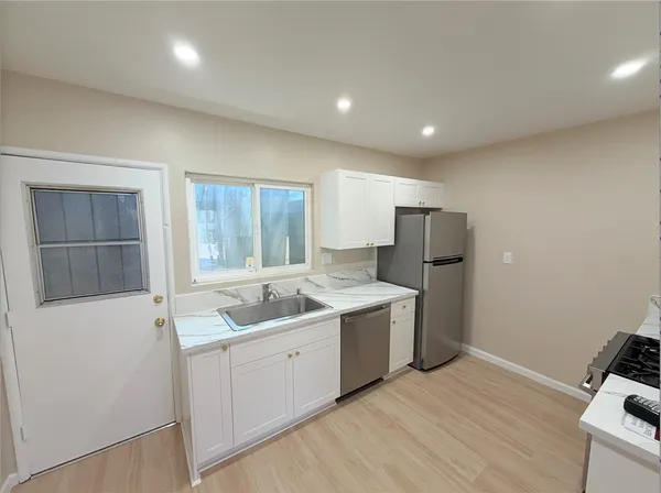 a view of a kitchen with a sink and dishwasher with wooden floor