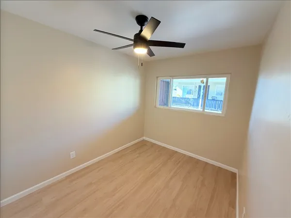 an empty room with ceiling fan and window