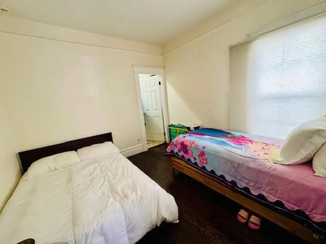 a bedroom with a bed and a dresser with wooden floor