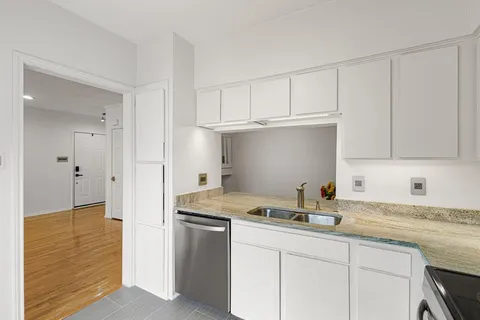 a kitchen with granite countertop white cabinets and a sink