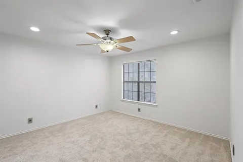 an empty room with windows and ceiling fan