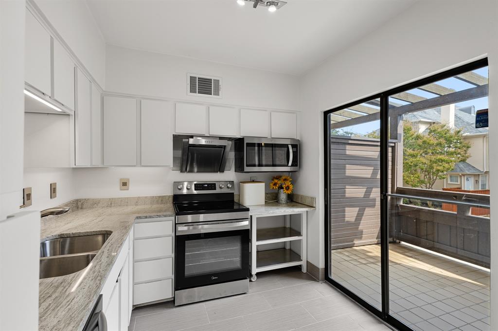 4130 Proton Drive, Unit 13A Addison, TX 75001 - Photo 9 of 40 Kitchen with appliances with stainless steel finishes, white cabinets, and light stone countertops