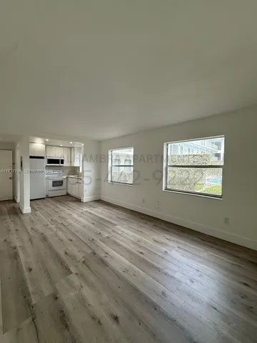 a view of empty room with kitchen and window