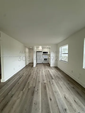 a view of empty room with wooden floor and window