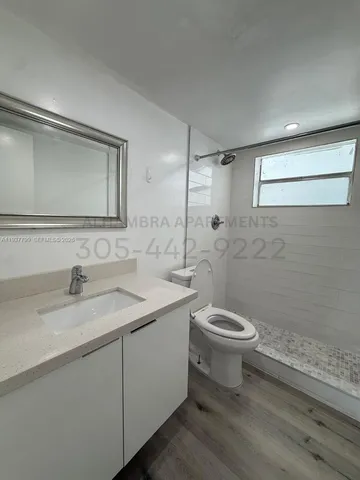 a bathroom with a granite countertop sink toilet and mirror