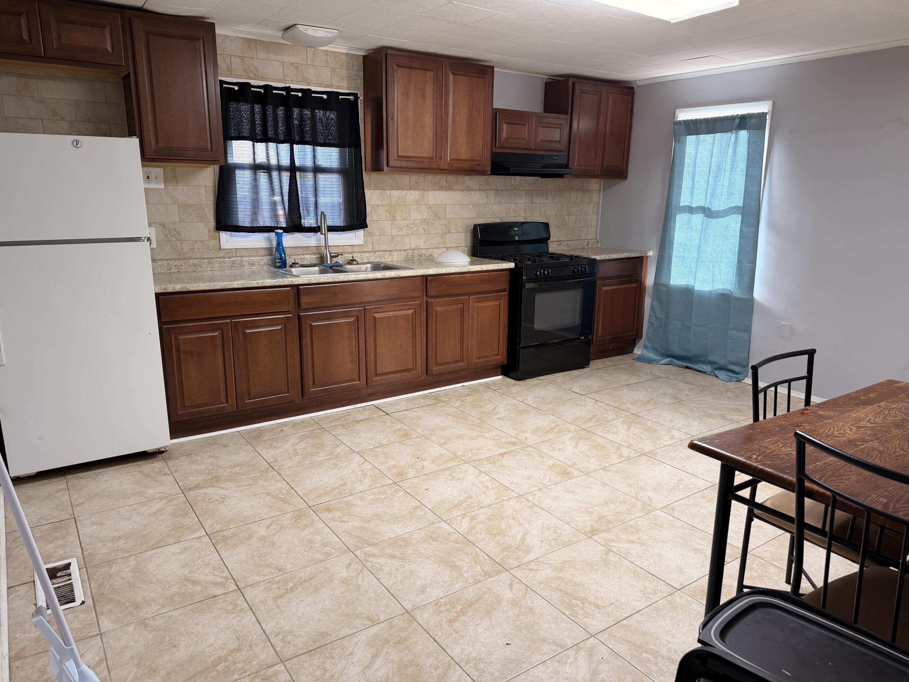 319 East Ridge Road Griffith, IN 46319 - Photo 4 of 10 a kitchen with stainless steel appliances a sink a stove a refrigerator cabinets a dining table and chairs