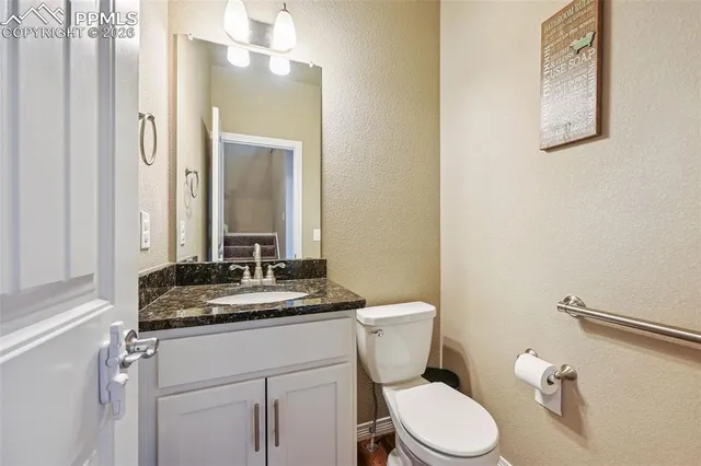 a bathroom with a granite countertop sink mirror vanity and toilet