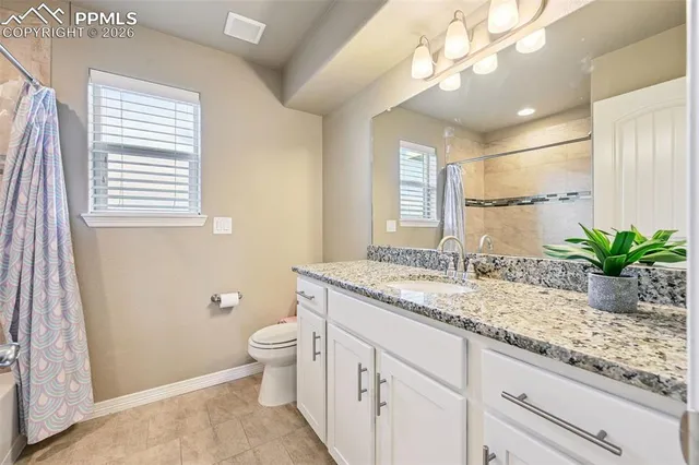 a bathroom with a granite countertop sink a toilet and a large mirror