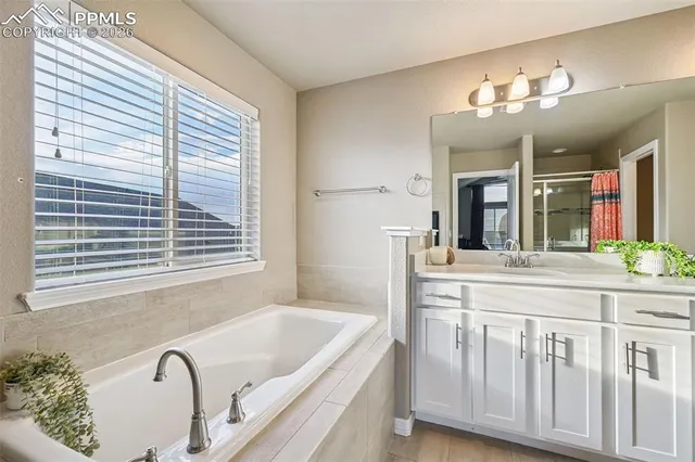 a bathroom with a granite countertop sink a large mirror and a bathtub next to a window