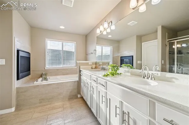 a large spacious bathroom with double vanity a window a bathtub and chandelier