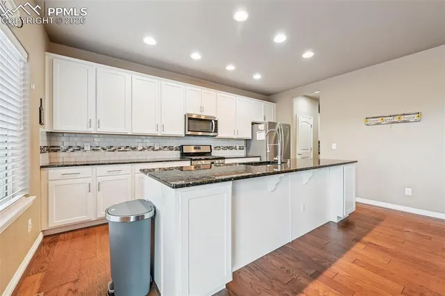 a kitchen with granite countertop white cabinets and white appliances