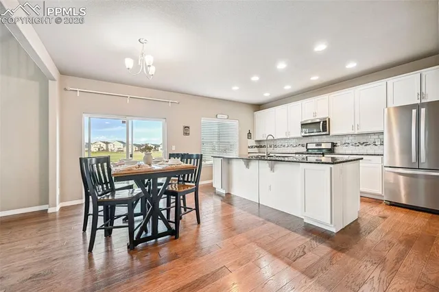a kitchen with stainless steel appliances a dining table chairs refrigerator sink and cabinets