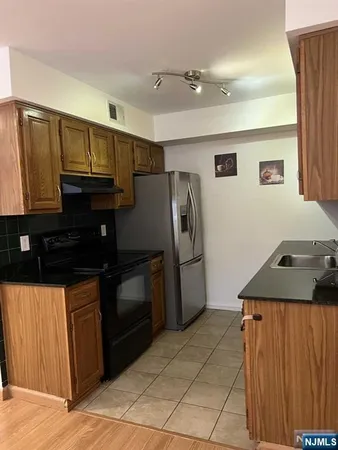 a kitchen with granite countertop a refrigerator and a stove top oven