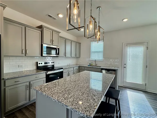 a kitchen with stainless steel appliances granite countertop a kitchen island hardwood floor sink stove dining table and chairs