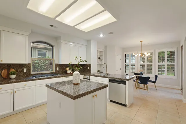 a kitchen with stainless steel appliances granite countertop a sink dishwasher and white cabinets with wooden floor